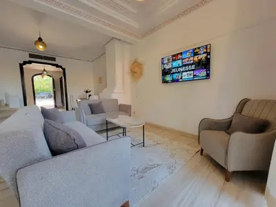 a living room with couches and a tv on the wall at Villa Camélia des 3 Z in Marrakech