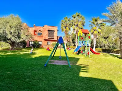 a park with children playing on playground equipment at Garden Villa-Style Retreat with Patio, BBQ & Pools in Marrakech