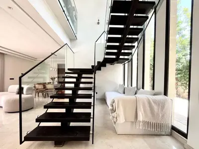 a black staircase in a white room with a bed at villa white in Marrakech