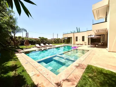a swimming pool with chairs and a house at villa white in Marrakech