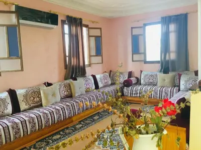 a living room with a long couch and windows at DaR CHAMSS in Marrakech