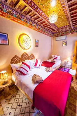 a bedroom with two beds with red sheets and a ceiling at Riad Almonds Marrakech in Marrakech
