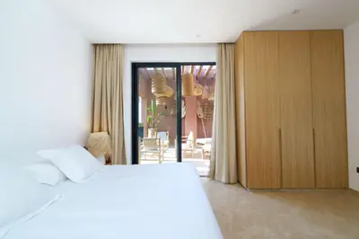 a bedroom with a white bed and a wooden cabinet at Dar Al Jenna - Villa de luxe avec piscine privée in Marrakech