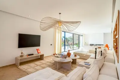 a living room with white furniture and a flat screen tv at Dar Al Jenna - Villa de luxe avec piscine privée in Marrakech