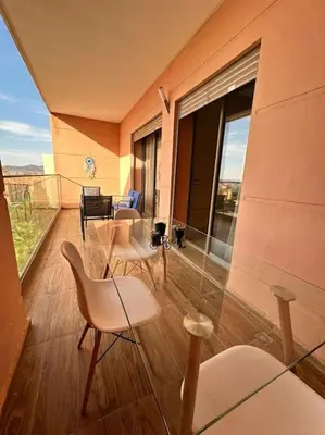 a balcony with chairs and a table and a large window at Appartement Cosy à Marrakech in Marrakech
