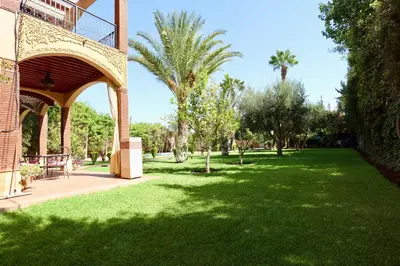 a green park with palm trees and a building at Villa Les Terrasses Des Jardins in Marrakech