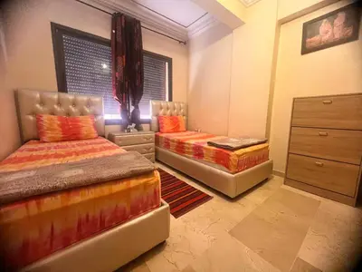 a bedroom with two beds and a dresser at prestige andalouse 4 in Marrakech