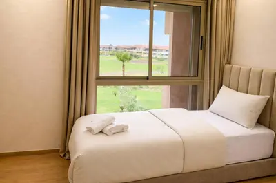 a bedroom with a white bed with a window at Expérience luxueuse Golf Prestigia Saphir BY KECH in Marrakech