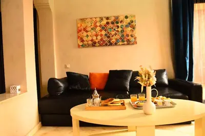 a living room with a black couch and a table at Oasis aux Palmeraies à Marrakech in Marrakech