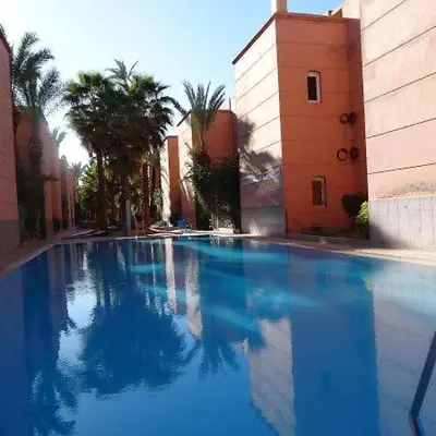 a large blue swimming pool with palm trees and a building at Riad with swimming pool in Marrakech