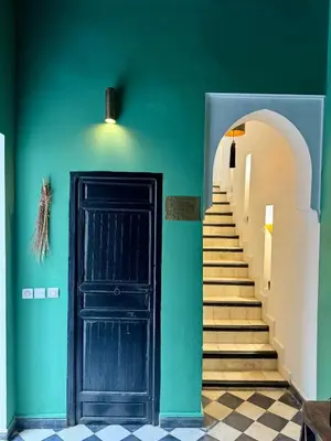 a stairway with a black door and a green wall at Riad privé luxe 3 chambres dans la médina de Marrakech y compris petit dejeuner in Marrakech