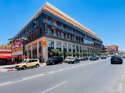 a building with cars parked on the side of a street at Cosy Appartement Centre Gueliz avec piscine in Marrakech