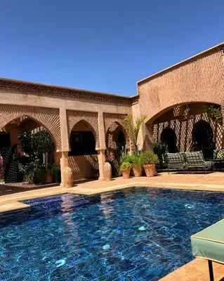 a large swimming pool in a building with chairs at Dar Anacaona in Marrakech