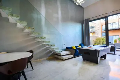 a room with a staircase and a table and chairs at Duplexe Luxueux de 2 Suites in Marrakech