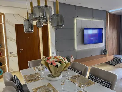 a dining room with a table with a vase of flowers at Prestigia 2 chambres vue piscine agate in Marrakech