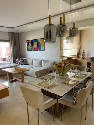 a living room with a table and a couch at Prestigia 2 chambres vue piscine agate in Marrakech