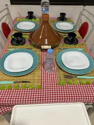 a dinner table with plates and a bottle of water at Ruime 2 kamer appartement 5 min van het centrum in Marrakech