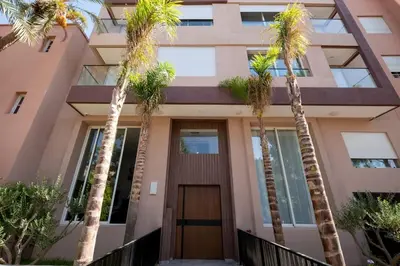 a building with palm trees in front of it at Luxury 2 Bedroom with Mountain View in Marrakech