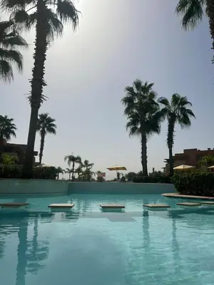a swimming pool with palm trees in the background at Prestigia corail in Marrakech