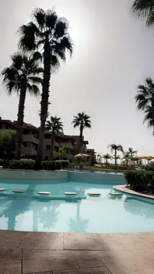 a large swimming pool with palm trees and a building at Prestigia corail in Marrakech