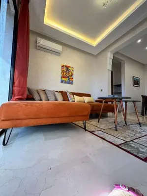a living room with an orange couch and a table at Appartement Sylia in Marrakech