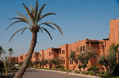 a palm tree in front of a brick building at Palacio Hôtel Condominium Marrakech in Marrakech
