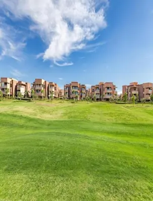 a golf course with apartment buildings in the background at Prestigia Marrakech golf city appartement 3 chambre in Marrakech