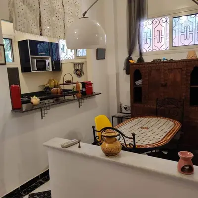 a kitchen with a counter with a table and a chair at Appartement T3 Le petit chat in Marrakech