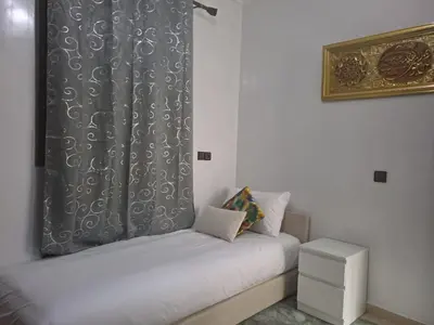 a bedroom with two beds and a curtain at Jardins d'Anas Appartement Airport in Marrakech