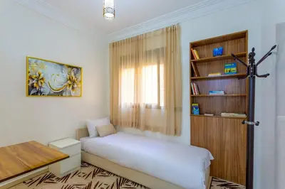 a bedroom with a bed and a book shelf at Jardins d'Anas Appartement Airport in Marrakech