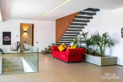 a living room with a red couch and a staircase at Magnifique villa sur front de golf Amelkis in Marrakech