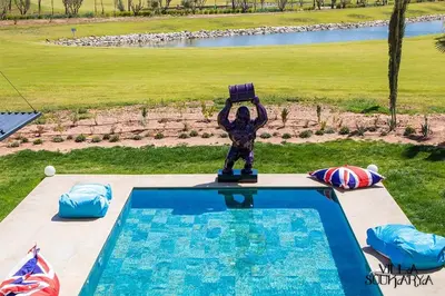 a statue standing next to a swimming pool at Magnifique villa sur front de golf Amelkis in Marrakech
