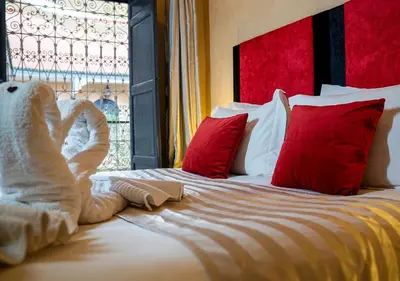 a bed with red and white pillows and a window at Riad Romance in Marrakech