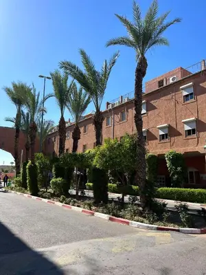 a building with palm trees in front of a street at Riad NYAH in Marrakech