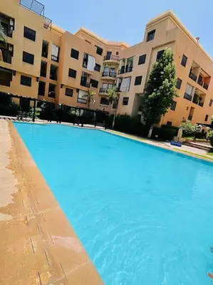 a large blue swimming pool in front of a building at Confort et Style Studio Chic avec Piscine in Marrakech