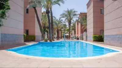 a large blue swimming pool in a building with palm trees at Riad Oued Issil in Marrakech
