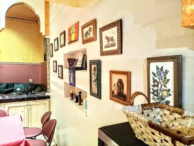 a kitchen with a table and some pictures on the wall at Riad Oued Issil in Marrakech