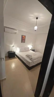 a white bedroom with a bed and two lamps at Rita 83 in Marrakech