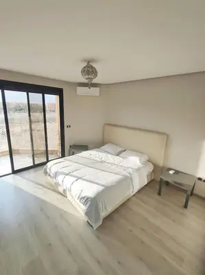 a white bedroom with a bed and a window at Appartement calme, proche de toutes commodités in Marrakech