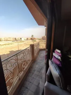 a balcony with a couch and a view of the desert at Appartement calme, proche de toutes commodités in Marrakech