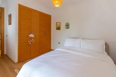 a bedroom with a large white bed and a wooden door at Peaceful apartment with a garden in Marrakech