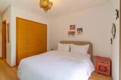 a bedroom with a white bed and a wooden door at Peaceful apartment with a garden in Marrakech
