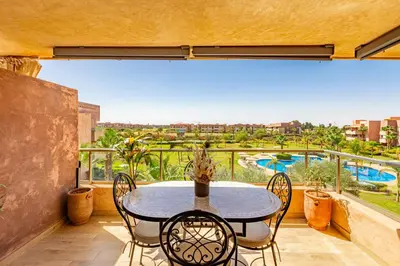 a patio with a table and chairs on a balcony at Serene Oasis Pool & Garden View in Marrakech