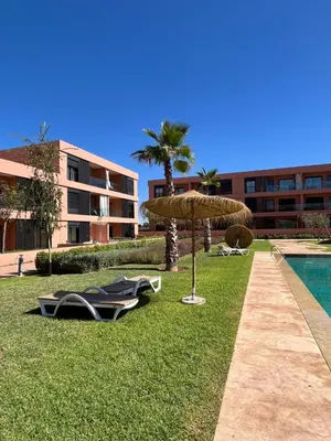 a resort with chairs and an umbrella next to a pool at Cozy Urbain Appartement in Marrakech