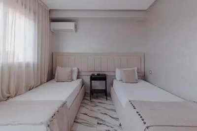 a room with two beds and a table in it at Zenitude séjournez en plein coeur de Marrakech in Marrakech