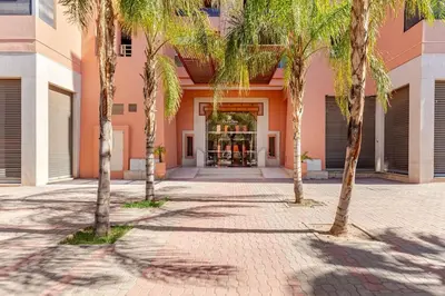 a courtyard with palm trees in front of a building at Appartement au cœur de Marrakech in Marrakech