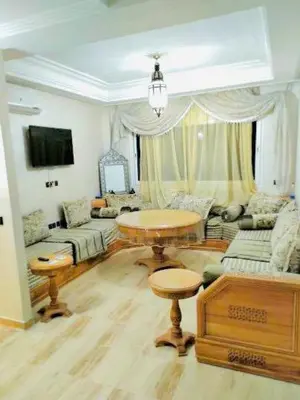 a living room with a table and a couch at Résidence Sakan Ennakhil in Marrakech