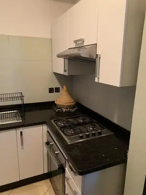a kitchen with a stove and white cabinets at Résidence Sakan Ennakhil in Marrakech