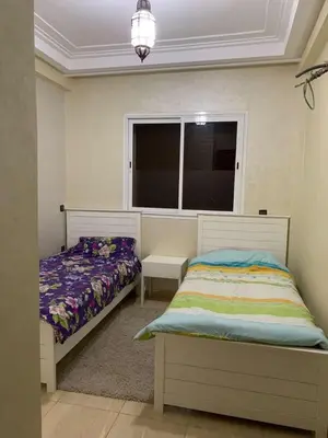 a bedroom with two beds and a window at Résidence Sakan Ennakhil in Marrakech