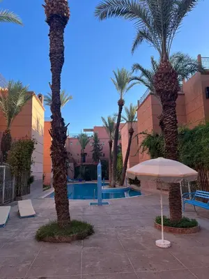 a resort with palm trees and a pool with an umbrella at Riyad piscine intérieure privative in Marrakech